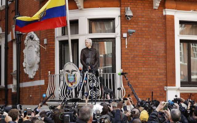Julian Assange mira desde el balcón de la embajada ecuatoriana antes de hablar en Londres. Foto: AP
