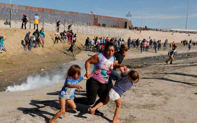 Una familia de migrantes, parte de una caravana de miles de personas que viajan desde América Central hacia Estados Unidos, huyen de gases lacrimógenos frente al muro fronterizo entre los Estados Unidos y México en Tijuana. REUTERS / Kim Kyung-Hoon