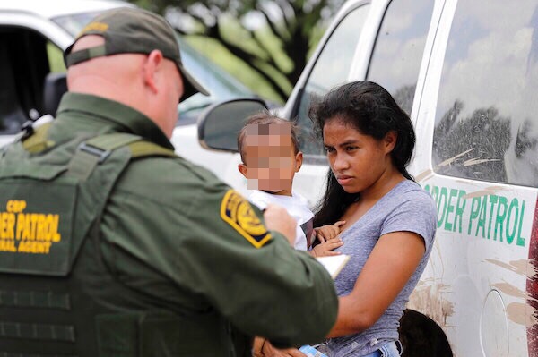 Una madre que migra de Honduras sostiene en sus brazos a su hijo de 1 año ante los agentes de la Patrulla Fronteriza de los luego de cruzar ilegalmente la frontera cerca de McAllen, Texas. Foto: AP