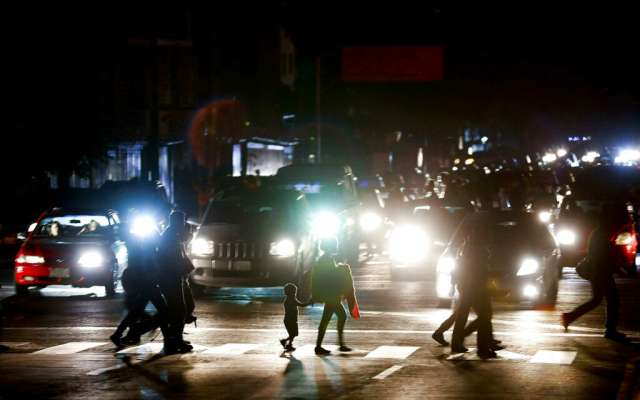 Residentes cruzan una calle de Caracas en la oscuridad tras el apagón que inició este jueves. Foto: AP
