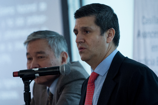 Héctor Díaz Santana frente a micrófono con edificios afuera de ventaja en segundo plano