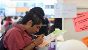Joven escribiendo sobre papel y con carteles de colores al fondo